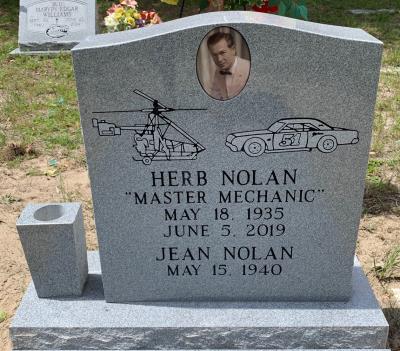 single upright gray granite headstone with race car and helicopter emblems